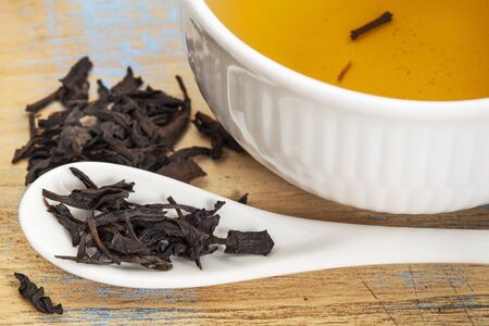 Se Chung Oolong tea - a white cup of drink and loose leaves on teaspoon