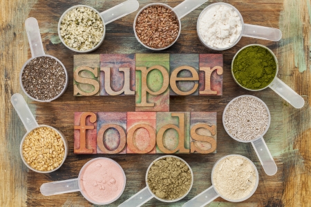 superfoods word in letterpress wood type surrounded by plastic scoops of healthy seeds and powders (chia, flax, hemp, pomegranate fruit powder, wheatgrass,  whey protein, maca root) - top viewの写真素材