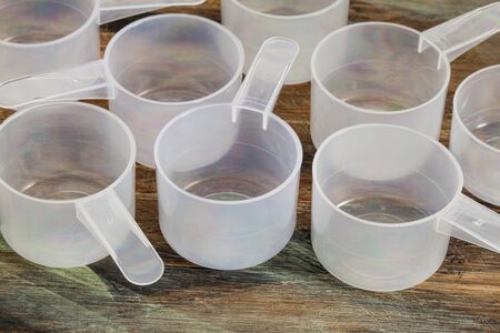 empty plastic measuring scoop on painted wooden board - nutrition conceptの写真素材