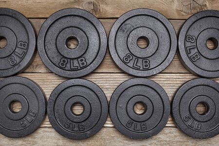background of exercise weights -  iron dumbbell plates on a wooden deckの写真素材