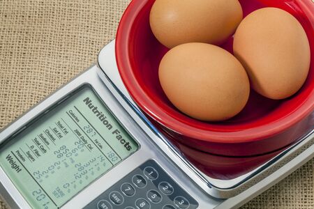 three eggs on diet scale displaying nutrition facts - a diet conceptの写真素材