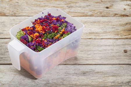 colorful juicer pulp after juicing raw vegetables (carrot, red beat, cucumber, kale, red cabbage) - a plastic cup against barn wood backgroundの写真素材