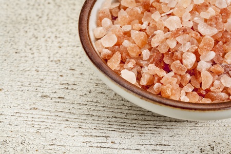 Himalayan salt coarse crystals in a ceramic bowl on  a rough white painted barn woodの写真素材