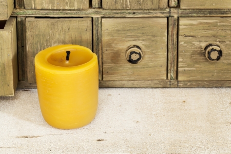 bee wax candle in retro setting with a primitive apothecary drawer cabinetの写真素材