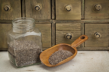 jar and scoop of chia seeds with a primitive apothecary drawer cabinetの写真素材