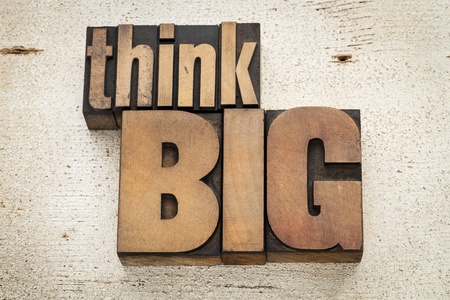 think big - motivation concept in vintage letterpress wood type on a grunge painted barn wood...