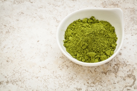 moringa leaf powder in a small bowl against a ceramic tile backgroundの写真素材