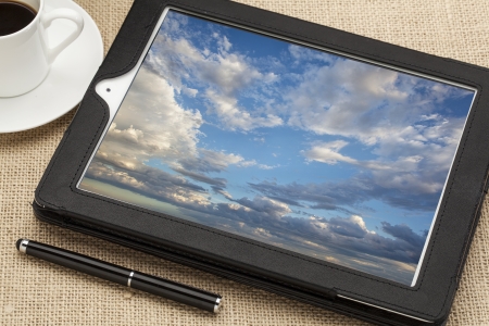 cloud computing concept - a stormy cloudscape on digital tablet computer together with a cup of...