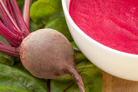 cream soup of red beets with a fresh beet root and leavesの写真素材
