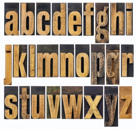 complete English lowercase alphabet - a collage of 26 isolated antique wood letterpress printing blocks, scratched and stained by inksの写真素材