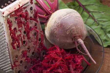 grated  red beets in preparation for soup with a fresh root and steel graterの写真素材