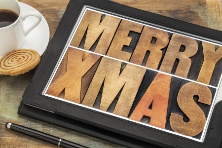 Merry Xmas in letterpress wood type on digital tablet computer with stylus pen, coffee cup and cookieの写真素材