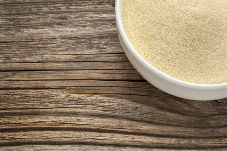 semolina wheat flour - a white ceramic bowl on a grained woodの写真素材