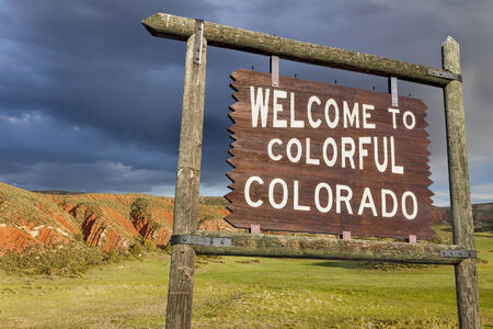 welcome to colorful Colorado roadside wooden sign with red sandstone cliff in backgroundの写真素材