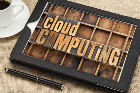 cloud computing - text in vintage letterpress wood type on a screen of digital tablet with a cup of coffeeの写真素材