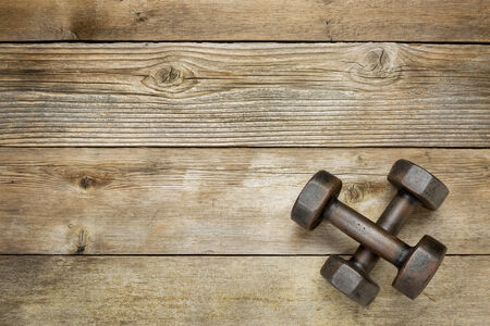 a pair of vintage iron rusty dumbbells on a weathered wood background with a copy spaceの写真素材