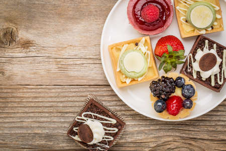 dessert - tarts with strawberry on white plate against grained weathered woodの写真素材