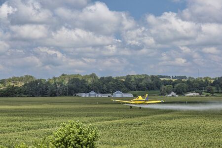 agriculture airplane dusting corn crops in Missouri farmland, selective focus on aircraft