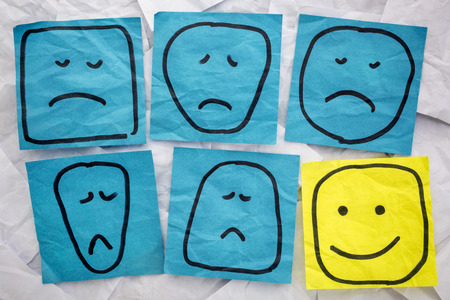 a set of sad, unhappy and happy, smiling faces - rough sketches on isolated blue and yellow sticky...