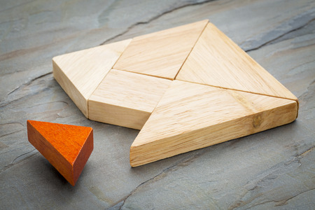 a missing piece in a square built from tangram shapes, a traditional Chinese puzzle game, slate rock...