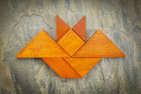 abstract picture of a flying bat built from seven tangram wooden pieces over a slate rock background, Halloween concept, artwork created by the photographerの写真素材