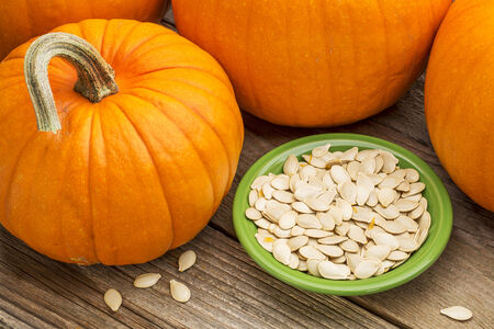 a bowl of fresh pumpkin seeds on weathered woodの写真素材