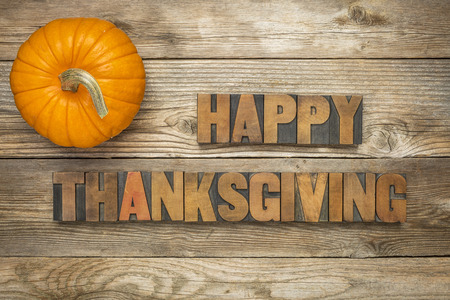 Happy Thanksgiving  - text in vintage letterpress wood type blocks against rustic wood background with a pumpkinの写真素材