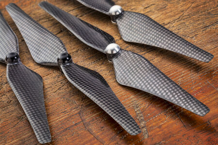 set  of four carbon fiber self-tightening propellers for a quadcopter drone against grunge woodの写真素材
