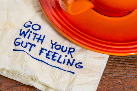 go with your gut feeling - advice or motivational reminder  on a napkin with cup of coffeeの写真素材