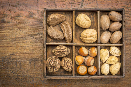 a variety of nuts (walnut, pecan, hazelnut, Brazilian and almond)  in a rustic wooden box against grunge wood surface with a copy spaceの写真素材