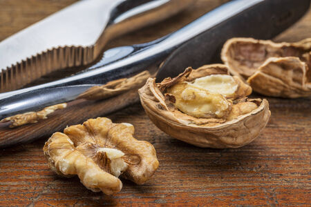 English walnuts with nutcracker against grunge wood background