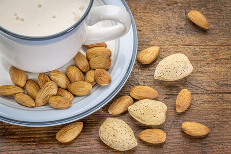 a cup of almond milk with almond nuts on a rustic barn wood tableの写真素材
