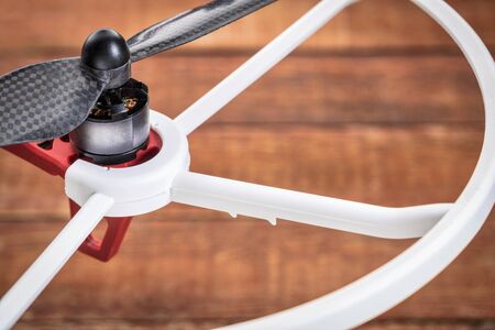 a detail of drone electric  motor, carbon fiber propeller and propeller guard over wood background