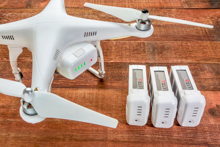 Fort Collins, CO, USA - March 17, 2015:  DJI Phantom 2 quadcopter drone with spare LiPo batteries, top view against rustic wooden table.のeditorial素材