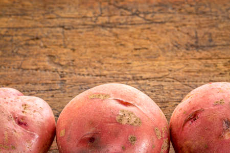 a row of three red potatoes on rustic wood with a copy spaceの写真素材