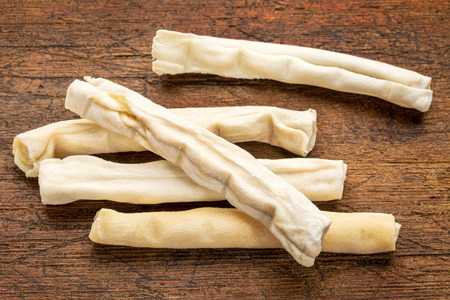 small rawhide bones - dog treats on grunge wood backgroundの写真素材