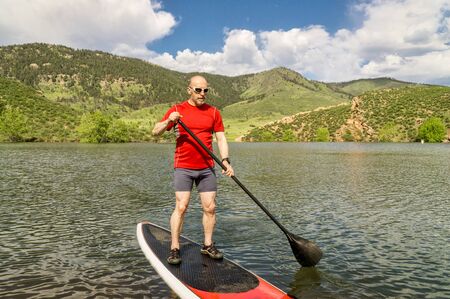 male paddler enjoying stand up paddling on a sunny summer day - Horsetooth Reservoir, Fort Collins, Coloradoの写真素材