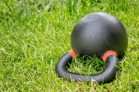 heavy iron competition kettlebell (62lb - 28 kg) on green grass in backyard - outdoor fitness conceptの写真素材