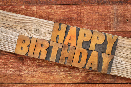 Happy Birthday greeting card - text in letterpress wood type printing blocks over rustic grained barn woodの写真素材