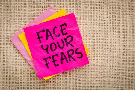 Face your fears advice or reminder on a sticky note against canvasの写真素材