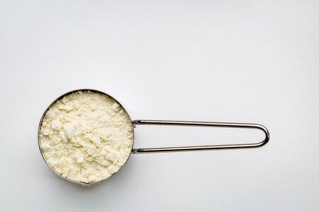 measuring metal scoop of whey protein powder against rustic white art canvas with a copy spaceの写真素材