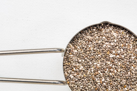 chia seeds in metal measuring coop against white art canvas with a copy spaceの写真素材