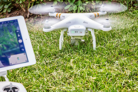 FORT COLLINS, CO, USA - AUGUST 28, 2015:   DJI Phantom 3 quadcopter drone with a radio controller and iPad Air tablet ready to take off from a backyard lawn.のeditorial素材