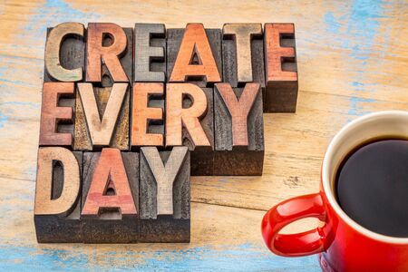create every day words in vintage letterpress wood type printing blocks against painted wood with a cup of coffeeの写真素材