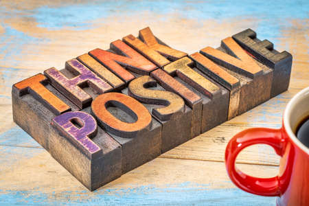 think positive inspirational words in vintage letterpress wood type blocks against grunge painted woodの写真素材