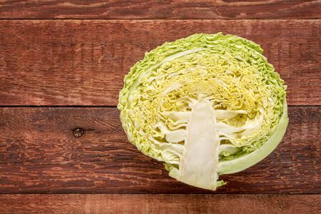 half of green savoy cabbage on red barn wood table with a copy spaceの写真素材