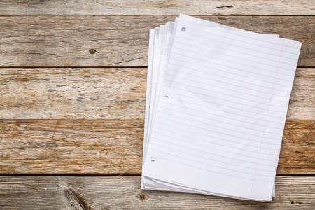 stack of blank notebook pages on a rustic, weathered wood backgroundの写真素材