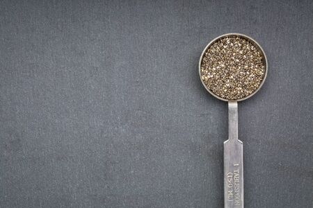 chia seed on metal measuring tablespoon against slate sone with a copy spaceの写真素材