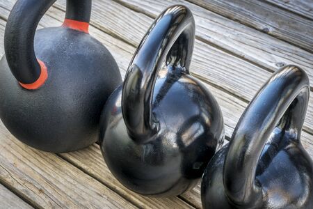 three heavy iron kettlebels on a wooden deck - fitness conceptの写真素材