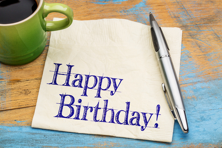 Happy Birthday greeting - handwriting on a napkin with a cup of coffeeの写真素材